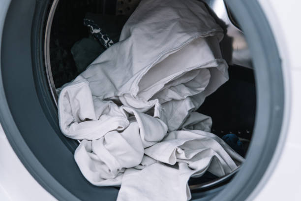 istock Dirty clothes in washing machine. Washing machine loading 1390494587
