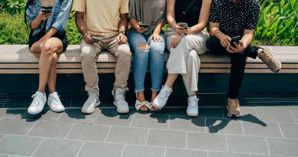 istock Group Of Five Unrecognizable Multi Ethnic Friends Using Mobile Phones and Having Fun Outdoors 1390495425