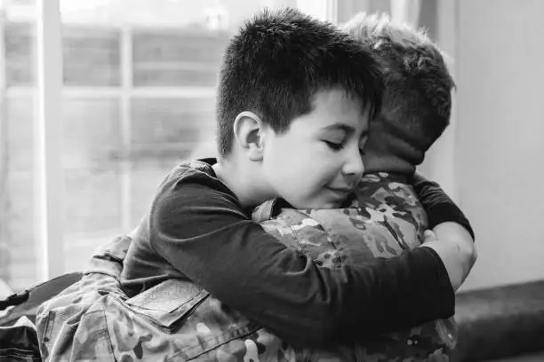 Veteran father hugging his kid son after homecoming reunion - Family love and war concept - Focus on child face - Black and white edition