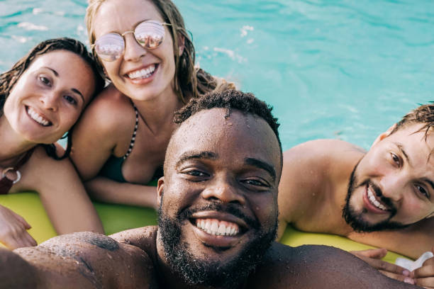 istock Multiracial friends at pool party having fun taking a selfie during summer vacation - Focus on african man face 1390496352
