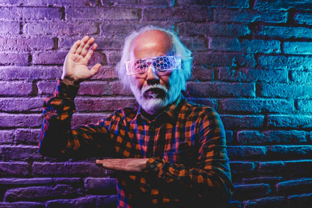 Senior Asian man dancing and playing with futuristic augmented reality glasses - Metaverse innovation new trend concept - Focus on left hand