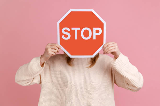 mulher escondendo o rosto com sinal vermelho, campanha contra a violência doméstica, proteção dos direitos das mulheres. - shirt problems red pink - fotografias e filmes do acervo