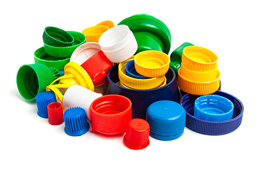 Colored plastic caps from bottles of water isolated on a white background. Close-up, top view. Recycling used plastic - a solution to the problem of plastic contamination.