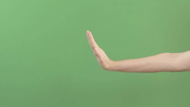 Hand gesture stop, NO sign. Woman stretches out her hand and making restriction gesture isolated on green screen chroma key background. Defense, disagreement, refusal, social distance