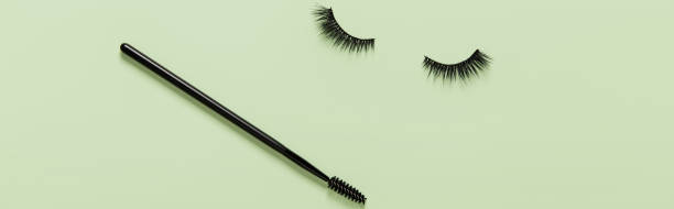 istock Creative layout with eyelashes and brush mascara. Closed eyes on green background 1390502607