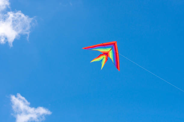 A kite flying in the sky among the clouds on a rope ( LGBT flag )