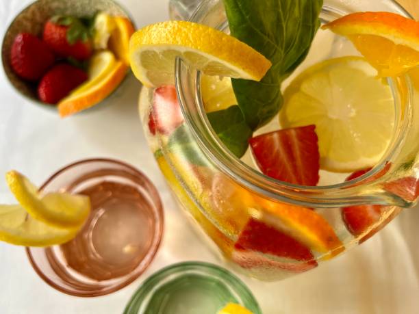 strawberry and lemon infused water in pitcher,  glasses and a fruit bowl  view from above strawberry and lemon infused water in pitcher,  glasses and a fruit bowl  view from above infused water stock pictures, royalty-free photos & images