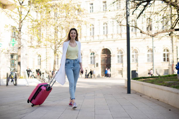 istock Young woman walking and pulling a small wheeled luggage 1390513831