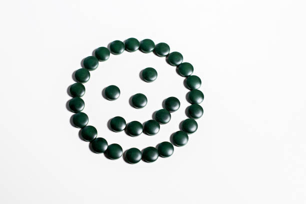 Spirulina tablets on a white background in the form of a smile. stock photo
