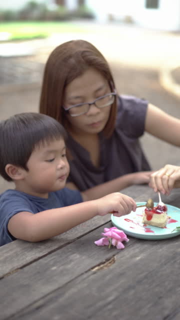 Asian Mother and little boy eating cheesecake at cake shop