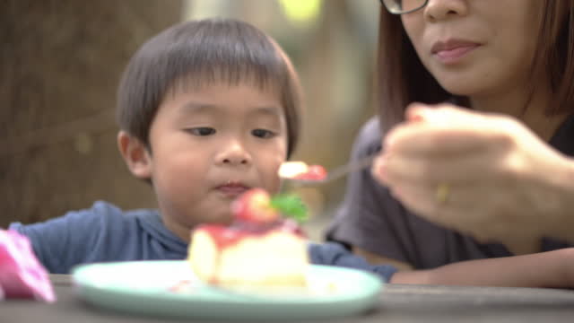 Asian Mother and little boy eating cheesecake at cake shop