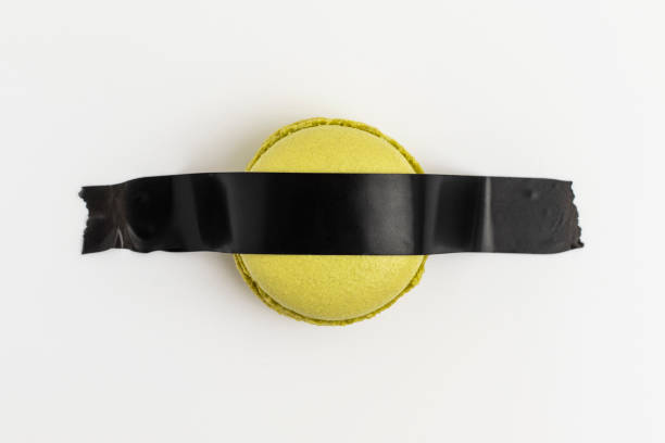 istock Green macaron is glued with black tape to a white background. 1390522798