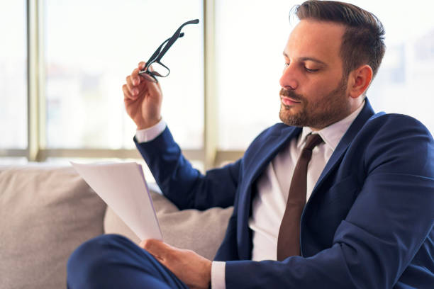 istock young bearded manager holding glasses and reading business document 1390527025