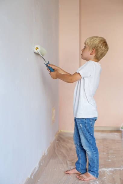 istock Home renovation. Young boy painting interior wall with paint roller 1390528310