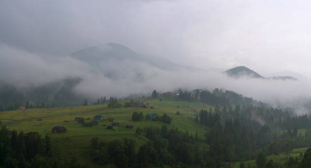 fog and rain in the carpathian mountains. mountain village dzembronya in the carpathian mountains, ukraine. panoramic photo of mystical mountain landscape. - eastern europe mountain range mountain village imagens e fotografias de stock