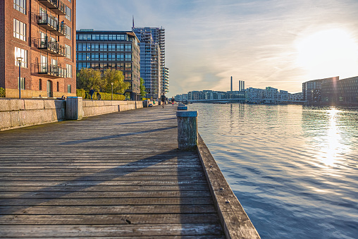 wooden embankment near the water of the canal and residential buildings at sunset. Copenhagen, Denmark