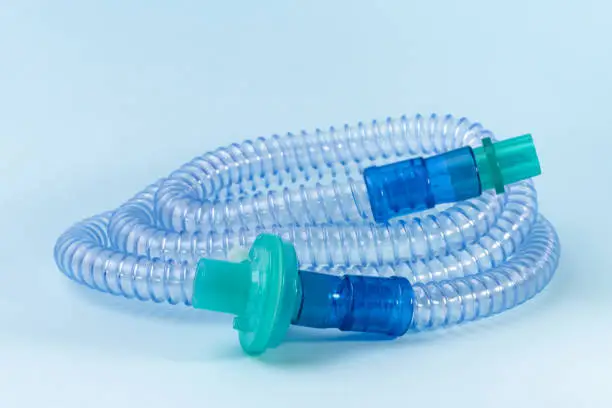 Photo of Tubing for CPAP or BIPAP machine with green filter isolated on blue background.