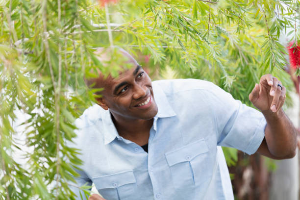 African-American man smiling as he walks under foliage