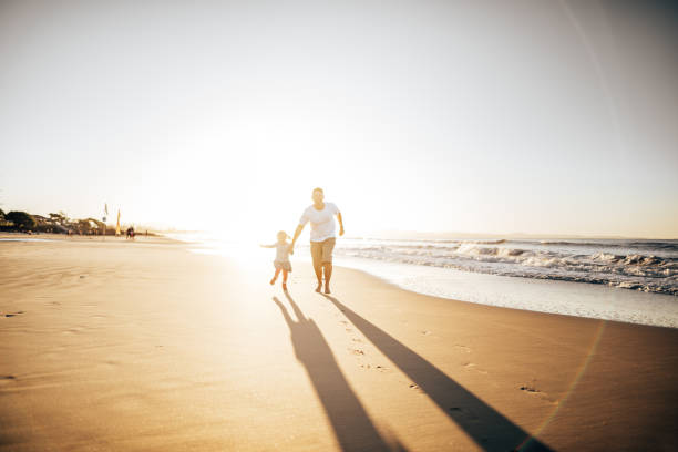 istock dad and daughter walking on the beach 1390535737