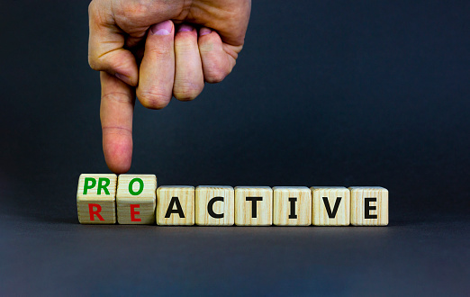 Reactive or proactive symbol. Businessman turns wooden cubes and changes the word reactive to proactive. Business and reactive or proactive concept. Beautiful grey background, copy space.