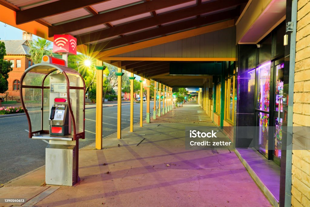 BH Argent Taxophone set Argent street pedestrian walkway pavement along displays of local shops and services with pay phone at sunset. Architecture Stock Photo