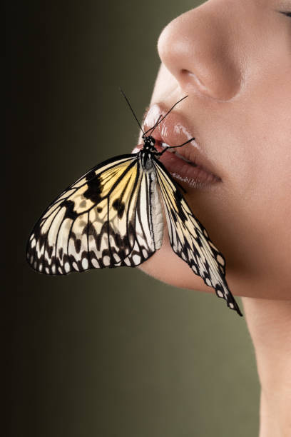 istock Butterfly on the girl face, green background 1390543548