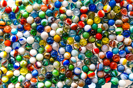Glass marbles are round colorful balls that children use to play a game. Background. Full-frame.