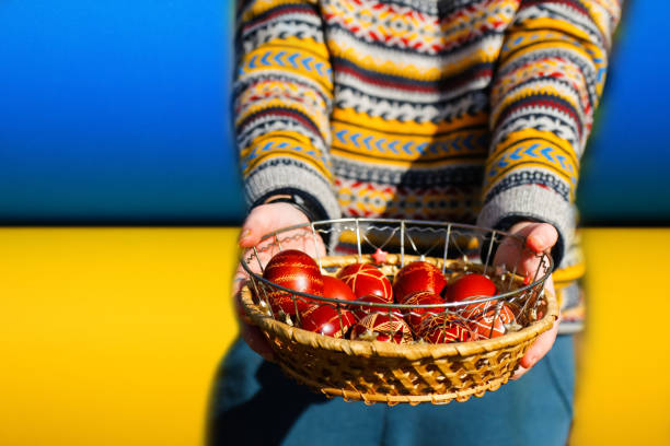 Defocus ukrainian young smiling woman in hat holding plate of collection of red egg on nature background. Easter, Ukraine flag. Craft painted eggs. Pysanka or krashanka. Closeup. Out of focus. desenfoque a la joven ucraniana sonriente mujer con sombrero sosteniendo el plato de la colección de huevo rojo sobre el fondo de la naturaleza. pascua, bandera de ucrania. artesanía de huevos pintados. pysanka o krashanka. closeup. fuera de foco