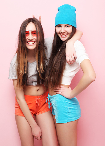lifestyle, people, teens and friendship concept - happy smiling pretty teenage girls or friends hugging over pink background