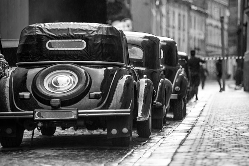 gloomy black retro cars stand on the street in front of a prohibition tape on a stone road