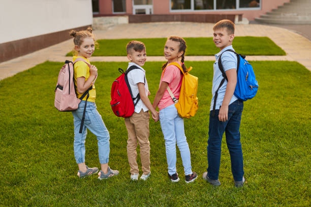 istock Schoolkids with backpacks on green yard 1390551518