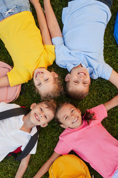 istock Happy schoolchildren lying on lawn 1390551544