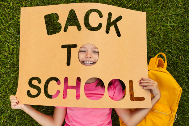 istock Schoolgirl lying on grass with banner Back To School 1390551548