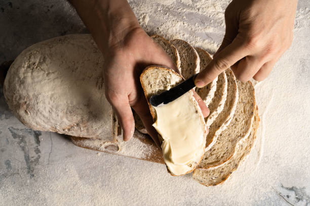 le mani maschili stendono il burro su una fetta di pane. - butter margarine fat bread foto e immagini stock