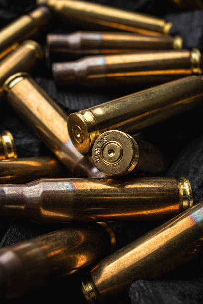 istock Empty shells from weapons on black smoldering coals. Consequences of the war. Dark background. 1390555358