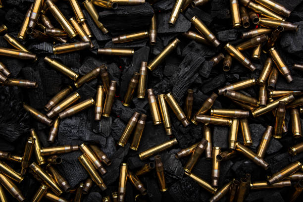 istock Empty shells from weapons on black smoldering coals. Consequences of the war. Dark background. 1390555361