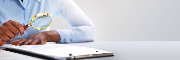 istock Businessperson Looking At Contract Form Through Magnifying Glass 1390560326