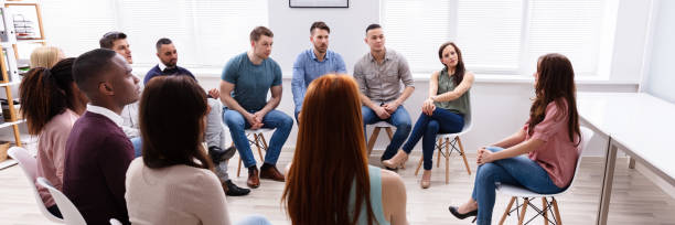 istock Female Therapist Speaking To Group At Therapy Section 1390560370