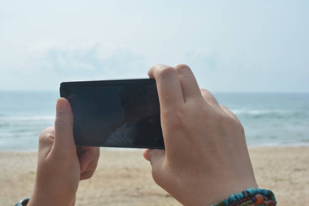 istock Woman holding landscape smartphone with blank screen while On the beach 1390563574