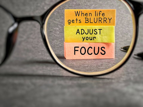 Inspirational and motivational quote. When life gets blurry, adjust your focus. Text written on notepaper background.