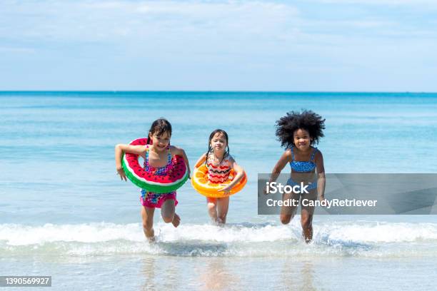 Little African And Asian Girl Playing In Sea Water Together At Tropical Beach On Summer Vacation Stock Photo - Download Image Now