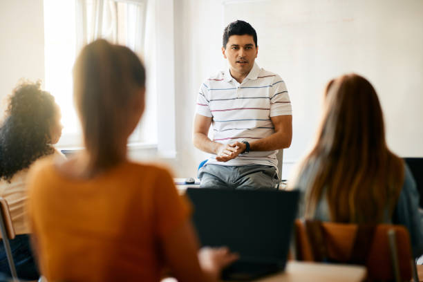 istock Computer science teacher giving lecture to group of high school students in the classroom. 1390581155