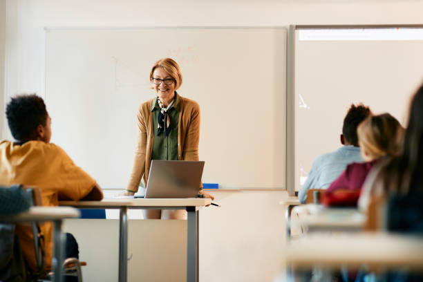 istock Happy mature teacher talking to her elementary students during a class at school. 1390581410