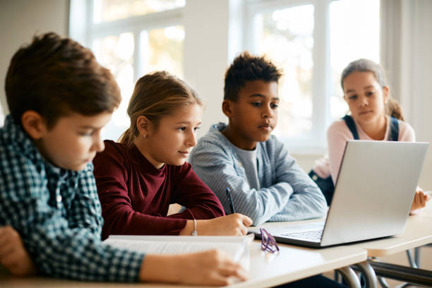 istock Group of elementary school classmates e-learning on laptop in the classroom. 1390581433