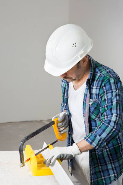 istock A builder in a safety helmet cuts a construction molding with a hacksaw during a house renovation 1390583267