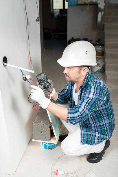 istock An electrician builder in a protective helmet measures the voltage with a voltmeter of an electrical cable in an outlet during construction, house renovation 1390583714