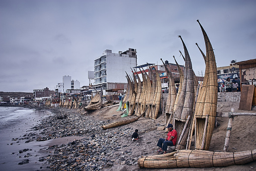 Huanchaco - July 13, 2018 : View of town and reed canoes commonly called by locals as Caballitos de Totora, a traditional way of sailing used by Fishermen from the North of Peru