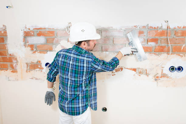 istock Builder repairman in a protective helmet plastering a brick wall with a putty knife during the repair of a house, apartment, room 1390584498