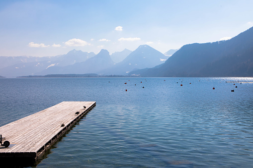 Panoramic view of an austrian lake with wooden pier and mountain range in the background. Salzkammergut Upper Austria