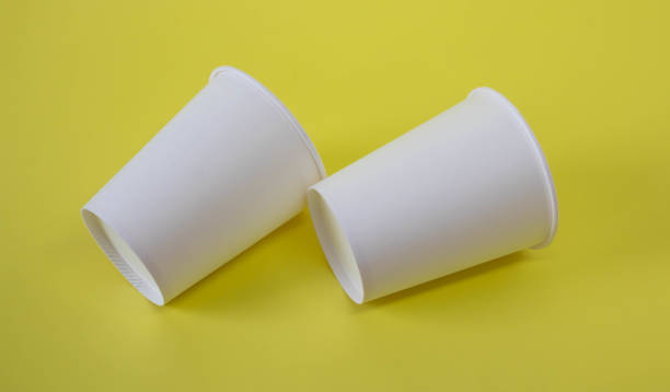 istock Two small white paper cups on a yellow background 1390602892
